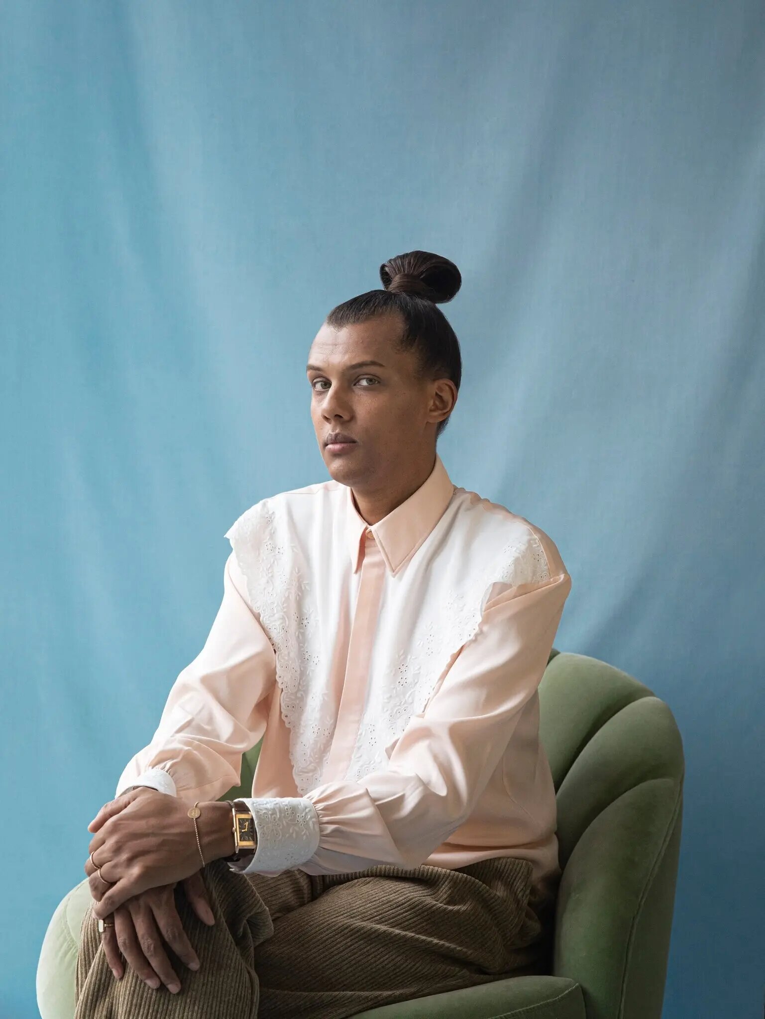 Portrait de Stromae assis sur fond bleu